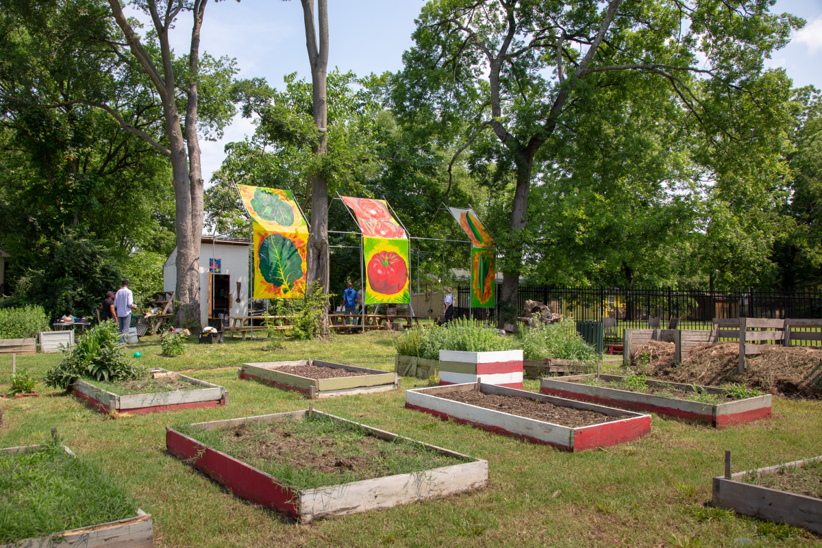 An outdoor speakeasy at Brooklyn Heights Community Garden in North Nashville installed by Seitu Jones. The speakeasy features three panels featuring vegetables painted on canvas, five picnic tables, and an outdoor bread oven. Photo by Stacey Irvin, 2018.