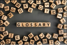 A photo of small wood letter tiles spelling out the word "glossary."