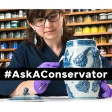 Photo of a person wearing purple gloves and cleaning a blue and white ceramic vase, with overlaid text that reads #AskAConservator