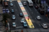 Bird's eye view of a city street with a colorfully painted striped mural on the median where people stand and walk bikes.
