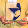 Close up photo of the leadership award, a clear glass square with half of the blue Americans for the Arts star, being held by a person in a yellow cardigan.
